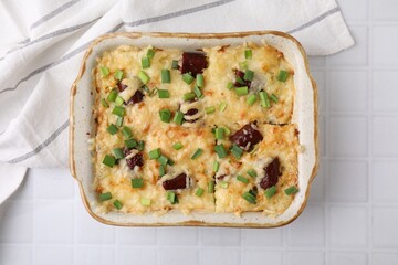 Tasty sausage casserole in baking dish on white tiled table, top view