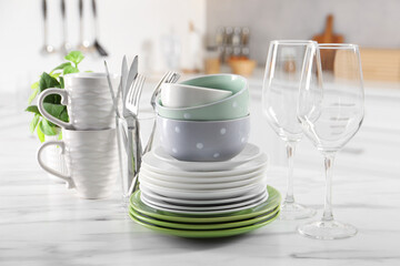 Many different clean dishware, glasses, cups and cutlery on white marble table indoors