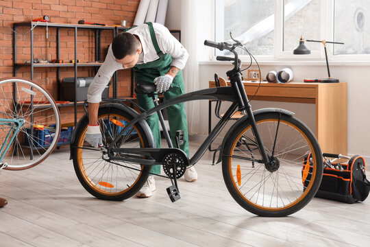 Young mechanic repairing bicycle wheel in workshop