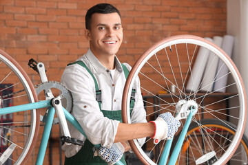 Young mechanic repairing bicycle wheel with wrench in workshop