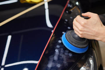 Person using machine to polish black cars automotive exterior