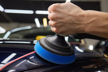 Person using machine to polish black cars automotive exterior