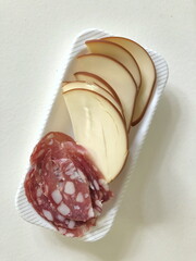 delicious smoked cheese slices and hard smoked sausage with lard on a plate, top view