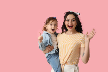 Beautiful pin-up woman and her daughter on pink background