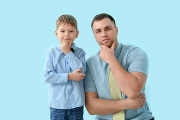 Thoughtful father and his little son on blue background