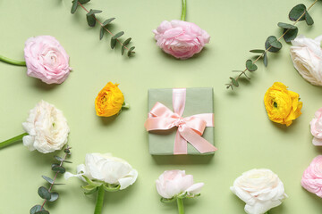 Gift box with beautiful ranunculus flowers and eucalyptus on green background