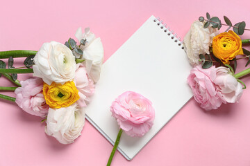 Beautiful ranunculus flowers with eucalyptus and open notebook on pink background