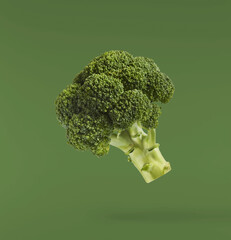 Fresh raw Brocolli cabbage falling in the air isolated on green backround. Healthy food levitation. High resolution image