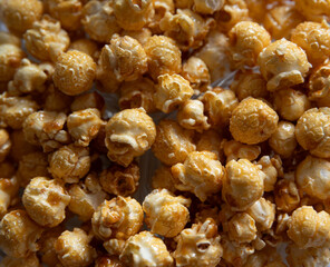 A close up of popcorn caramel with a light brown color. The popcorn is scattered all over the image