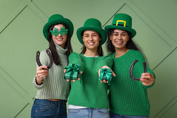 Beautiful young women in leprechaun hats with gift boxes and horseshoes on green background. St....