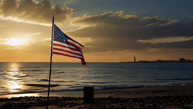 An American flag blowing in the wind, stuck in the sand of a beach. A sunset with the sun almost setting over the sea horizon. The waves on the seashore reflect the golden light of the sunset