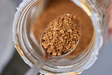 Woman stirs instant coffee in glass mug with boiled water on grey stone table
