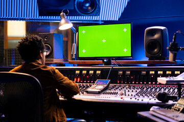 African american sound designer works with greenscreen monitor, mixing and mastering tracks on...