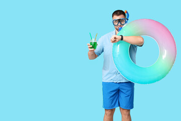 Shocked office worker in diving mask with inflatable ring and cocktail looking at wristwatch on...