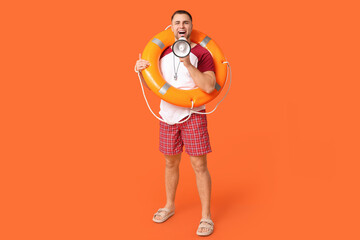 Happy young lifeguard with lifebuoy and megaphone on orange background