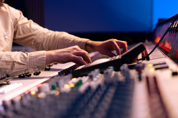 Audio expert uses mixing console and switchers on control room panel, adjusting sound on mixer....