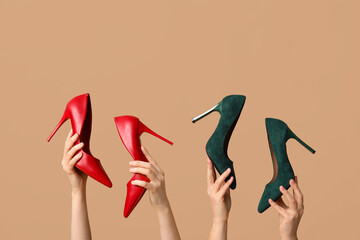 Female hands with different stylish high heels on brown background