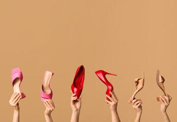 Female hands with stylish sandals and red high heels on brown background