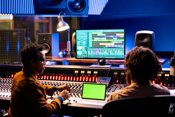 Musician and sound producer look at isolated mockup on tablet, using mixing and mastering...