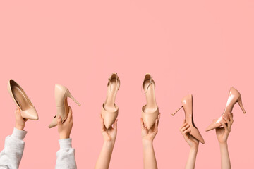 Female hands with stylish beige high heels on pink background