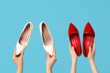 Female hands with different stylish high heels on blue background