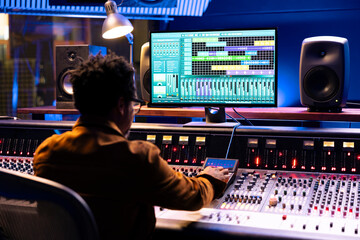 African american audio expert operating editing software to adjust sound settings, control room...
