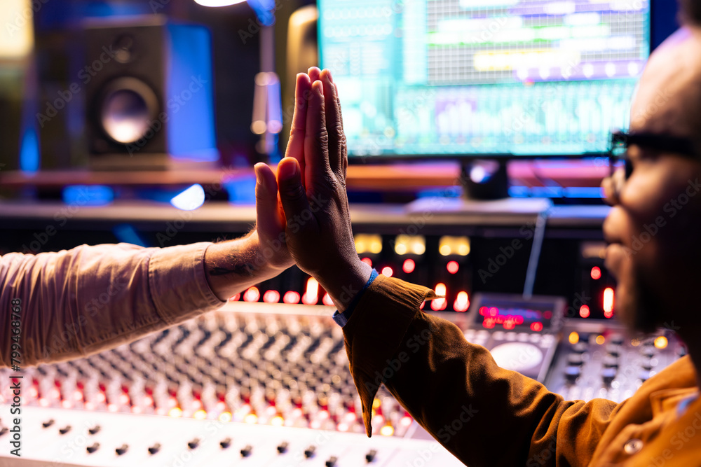 Poster pleased artist doing high five gesture with sound designer after finishing a song, processing and ed