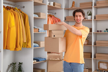 Handsome young happy man with wardrobe boxes and stylish clothes in dressing room