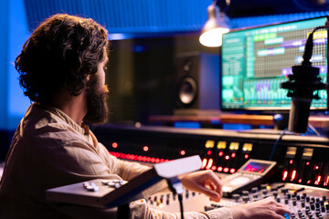 Sound designer editing music with digital audio software on pc, recording and processing sounds in...