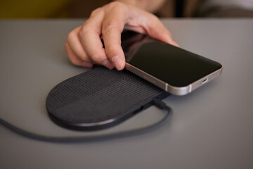 Man Charging Smartphone Using Wireless Charging Pad At Home