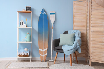 Interior of stylish living room with grey armchair and surfboard