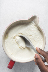 Homemade greek yogurt in a ceramic spoon, process of making Greek yogurt, strained thick yogurt in...
