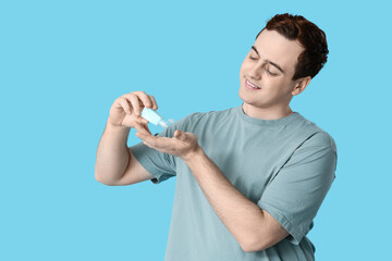 Young man with sanitizer on blue background