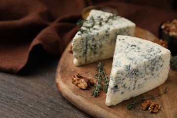 Tasty blue cheese with thyme and walnuts on wooden table, closeup. Space for text