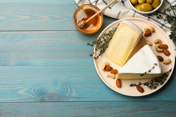 Tasty Camembert cheese with thyme, honey and nuts on light blue wooden table, flat lay. Space for text