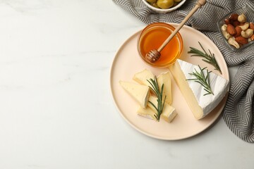 Tasty Camembert cheese with rosemary and honey on white table, flat lay. Space for text