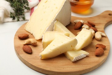Tasty Camembert cheese with honey and nuts on white table