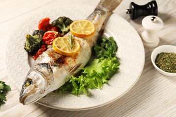 Delicious baked fish and vegetables served on wooden table, closeup
