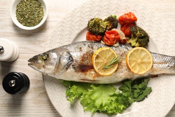 Delicious baked fish and vegetables served on wooden table, flat lay