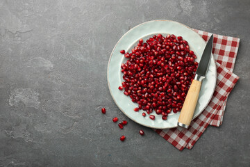 Tasty ripe pomegranate grains on grey table, top view. Space for text
