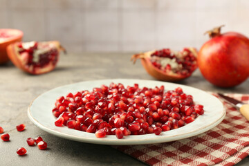 Tasty ripe pomegranate grains on grey table, closeup