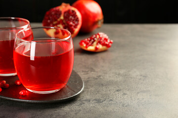Tasty pomegranate juice in glasses and fresh fruits on grey table, closeup. Space for text