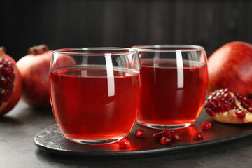 Tasty pomegranate juice in glasses and fresh fruits on grey table, closeup