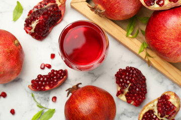 Tasty pomegranate juice in glass and fresh fruits on white marble table, flat lay