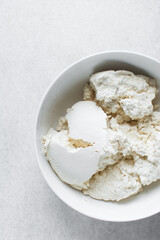 Strained Greek yogurt in a white ceramic bowl, process of making Greek yogurt, strained thick...