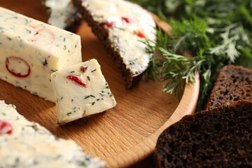 Tasty butter with dill, chili pepper and rye bread on table, closeup