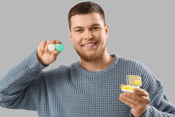 Young man with contact lenses on grey background, closeup