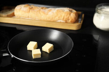 Melting butter in frying pan, bread and flour on black table