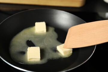 Stirring melting butter in frying pan on table, closeup