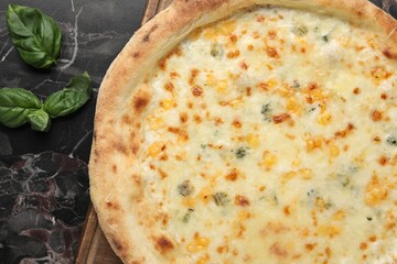 Delicious cheese pizza and basil on black marble table, flat lay